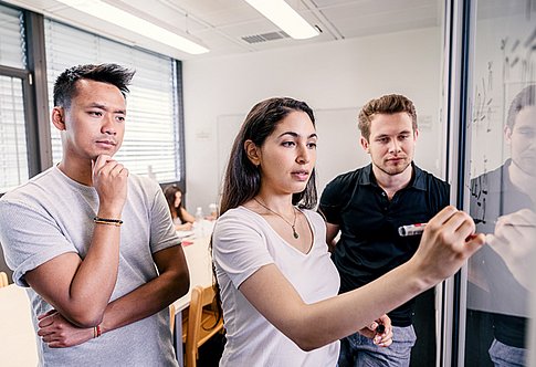 3 students discussing a problem at a whiteboard