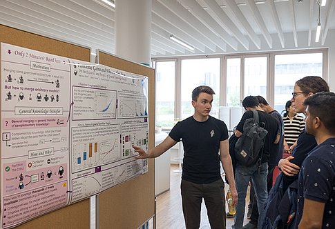 People are discussing a conference poster put up on a display panel
