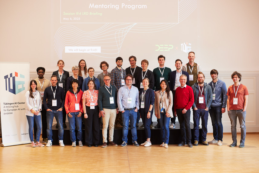 A group image of about 25 people standing in two rows. To the left, a Tübingen AI Center rollup (image: Tübingen AI Center / Nino Strauch)